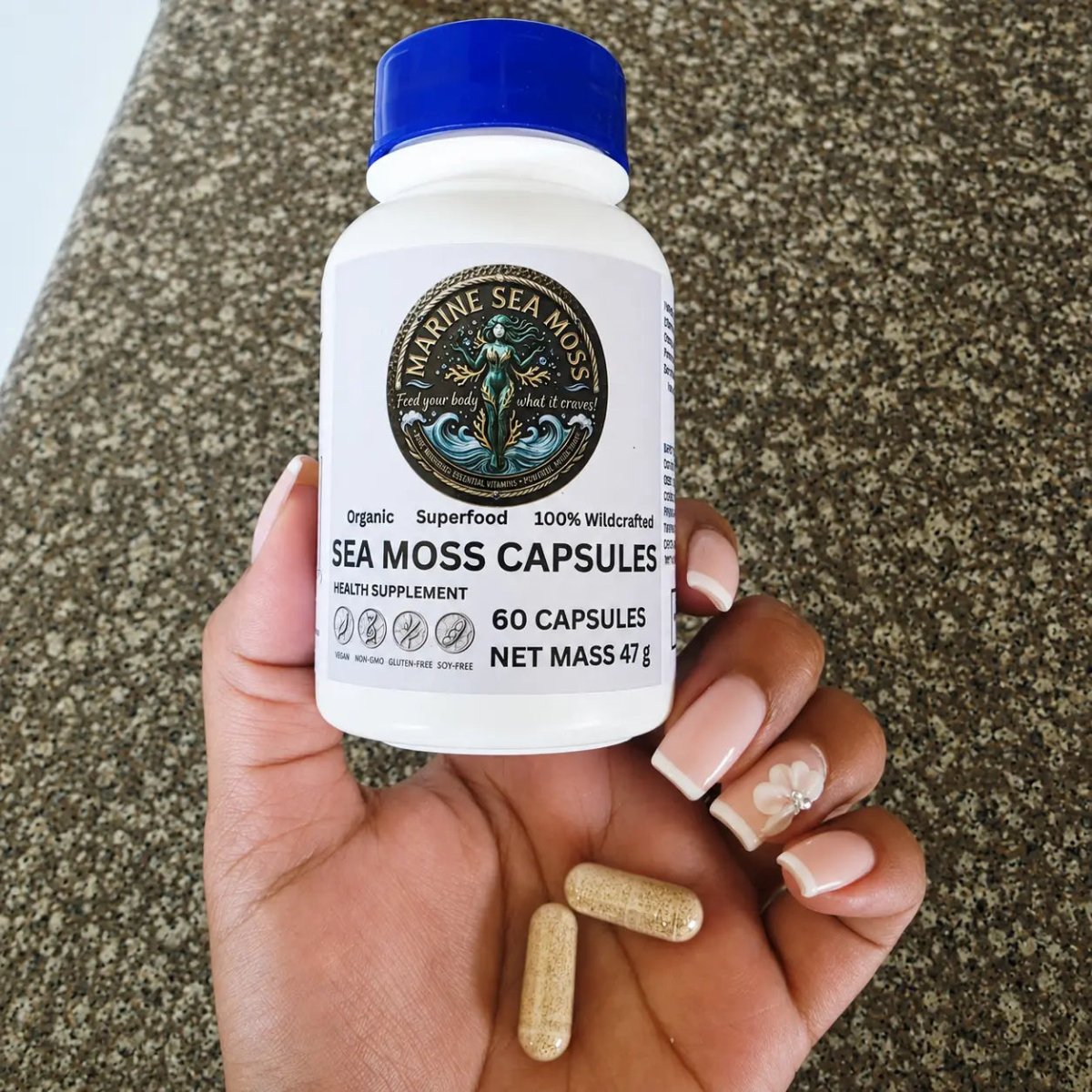 Hand holding Marine Sea Moss Capsules bottle with two sea moss capsules resting in palm