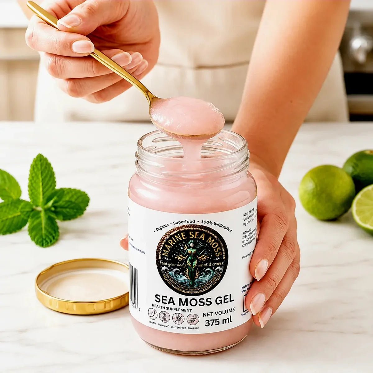 Hand scooping pink Marine sea moss gel from a 375ml glass jar with a golden spoon